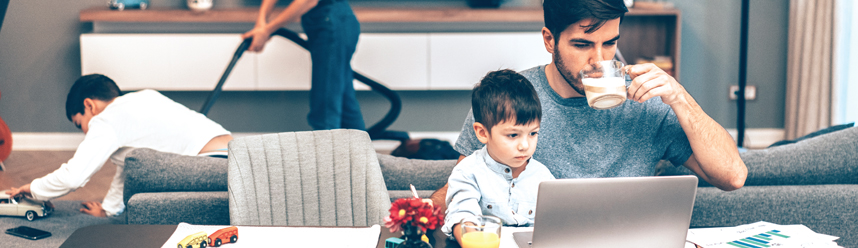 man looking at laptop with family in background man looking at laptop with family in background
