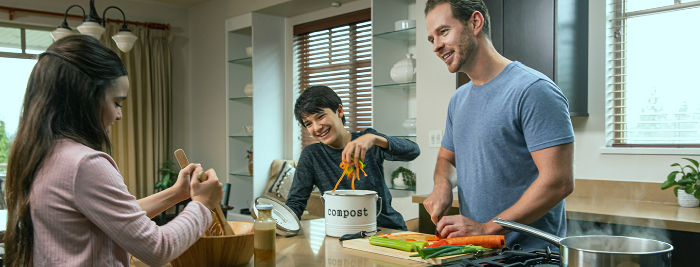 A family making dinner together while a boy placed kitchen scraps into a compost bin. (20-064.18) A family making dinner together while a boy placed kitchen scraps into a compost bin. (20-064.18)