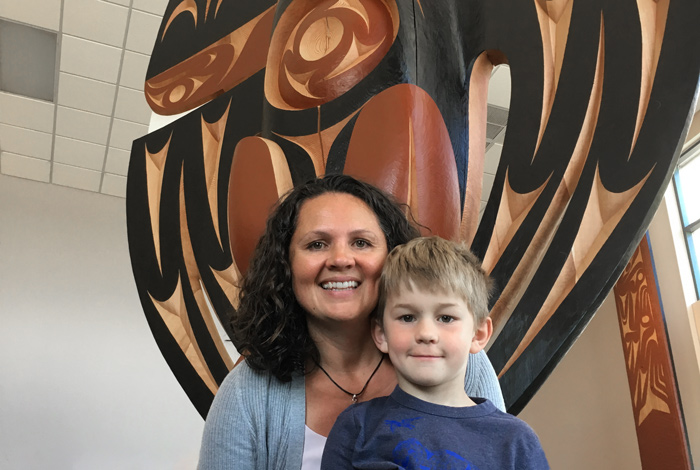 Carmen and Joshua in front of yuxwule’ or the Welcome Figure by Stz’uminus artist John Marston at Ladysmith Secondary School.