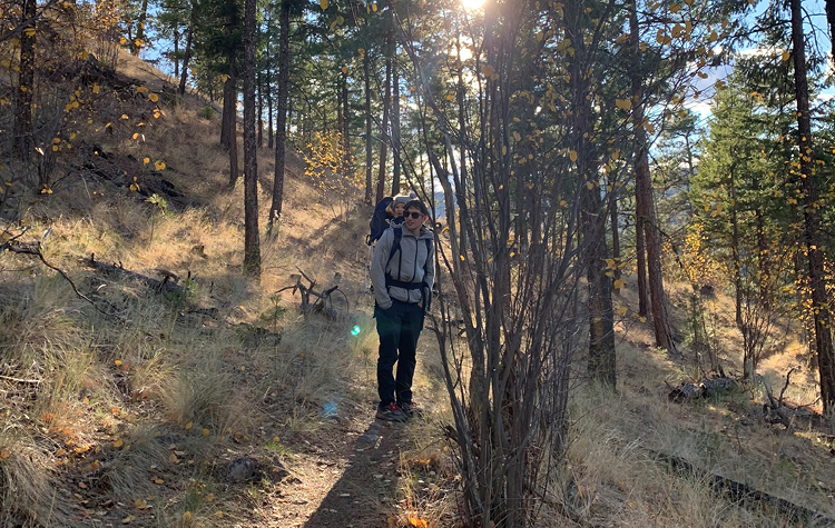 Jeremy Dresner standing in the shade while hiking with child on back