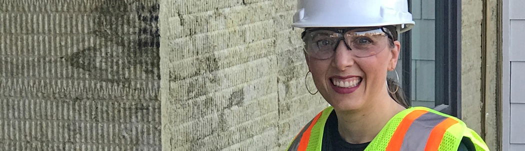 Homeowner Colleen wearing a hard hat beams over her home’s new innovative insulation sheathing