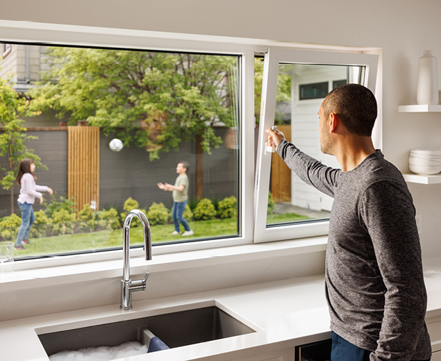 Shane opening the kitchen window, as the kids play outside