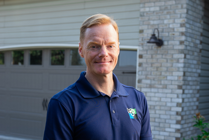 An energy advisor, standing and smiling outside a client’s home.