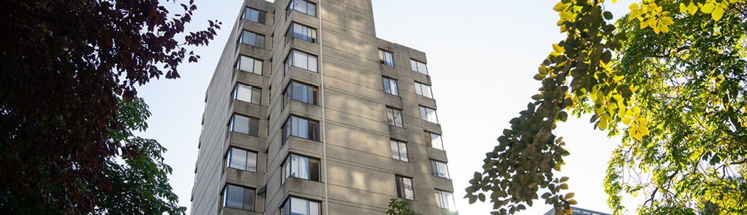 An older high-rise apartment building with trees around it.