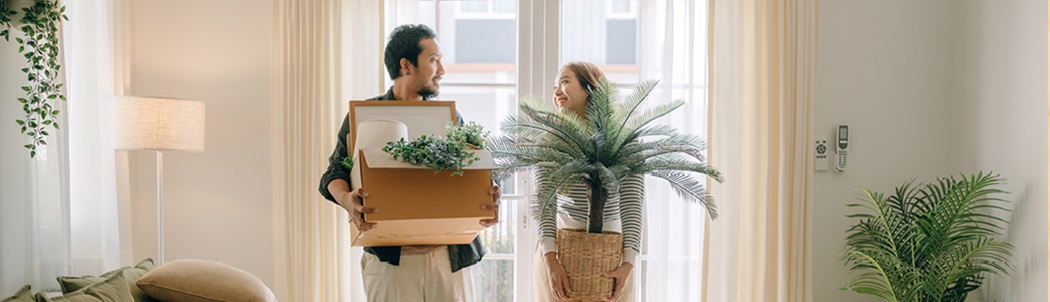 Man and woman carrying boxes and house plants.