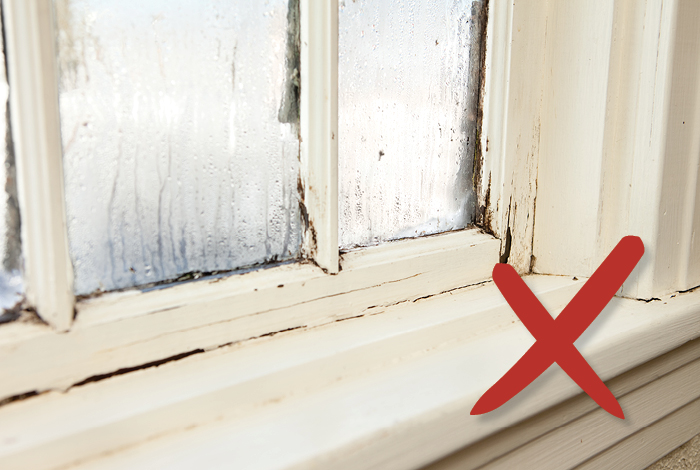 older window with condensation on panes with X in front of it.