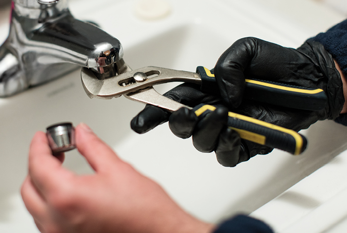 A handman installing a bathroom sink facent to a new low-flow version.