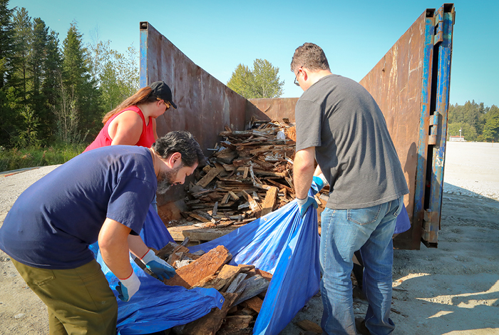 Volunteers transferring shoreline debris to a large garbage bin