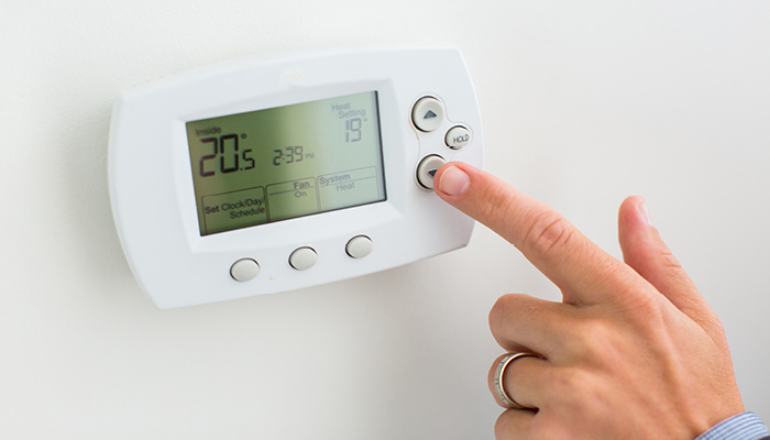 A person is programming their smart thermostat.