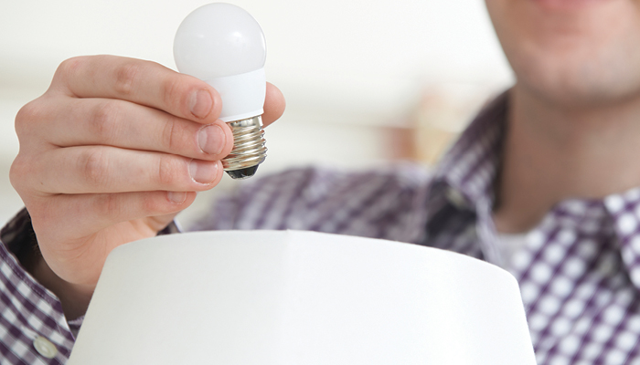 A man is about to change the lightbulb in a lamp to an energy-efficient LED one.