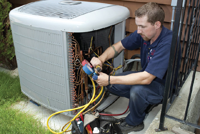 contractor inspecting a heat pump and performing routine maintenence