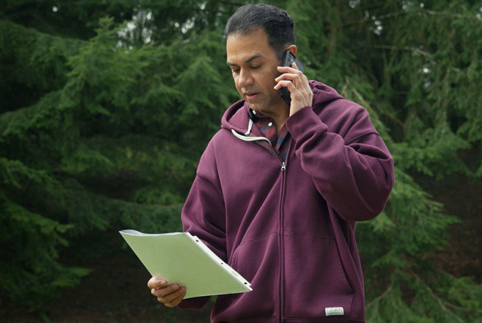 A man talking on his smart phone and refering to a BC 1 Call ticket package