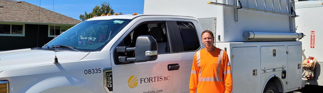 Lloyd Jones standing proudly in front of a FortisBC utility truck