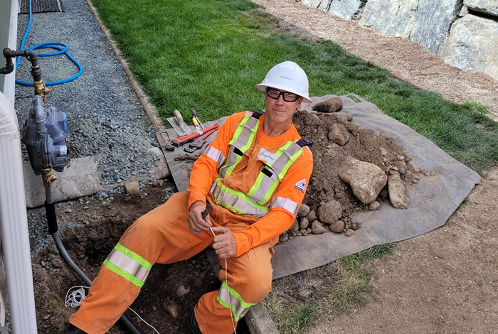 Lloyd Jones sitting beside a home, smiling and working on a gas meter