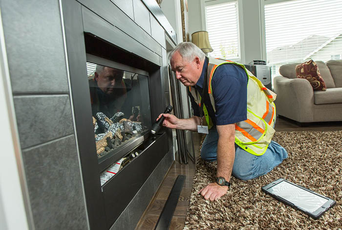 A contractor inspecting a gas fireplace with a flashlight.
