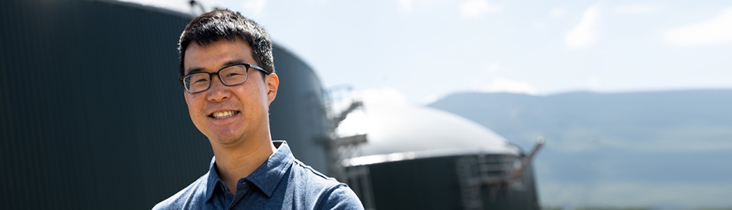 Mason Lau, a senior engineer stands in front of a biofuel facility.