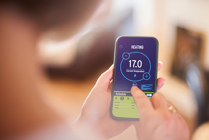 A person controlling a thermostat with their phone.