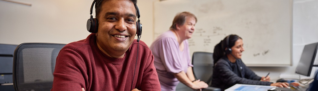 A smiling employee wearing a headset with a microphone, posing confidently.
