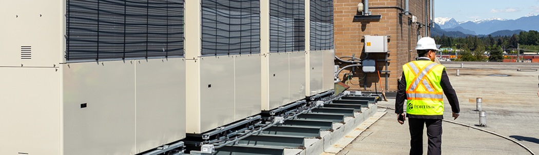 Man walking alongside a series of gas engine-driven heat pumps.