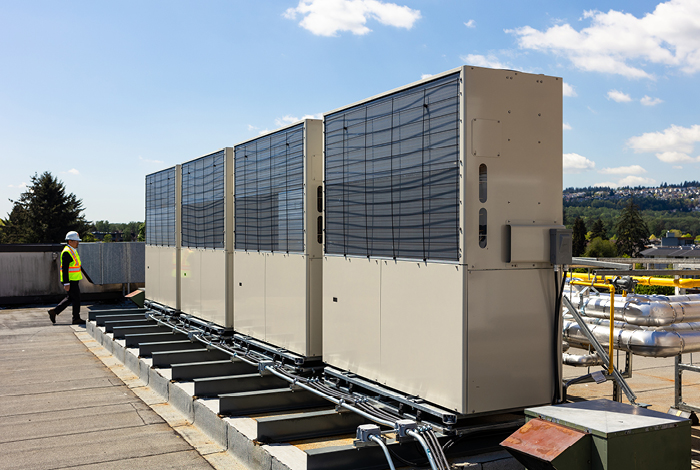 Man walking toward a series of gas engine-driven heat pumps.
