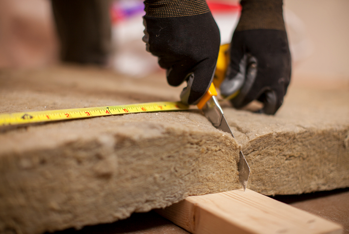 A contractor measuring and cutting batt insulation