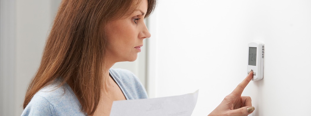 Woman reaching to adjust her thermostat