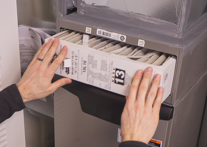 A pair of hands changing an air filter.
