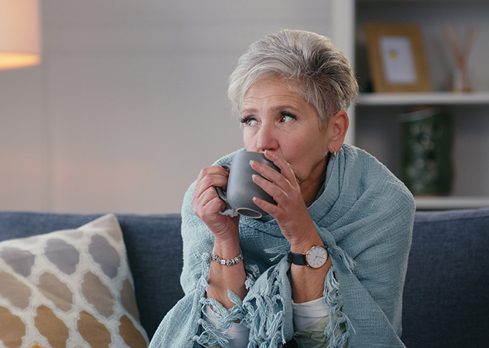 A woman sitting on a couch drinking out of a mug.
