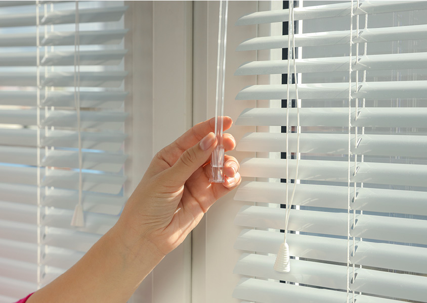 A person closing window blinds.