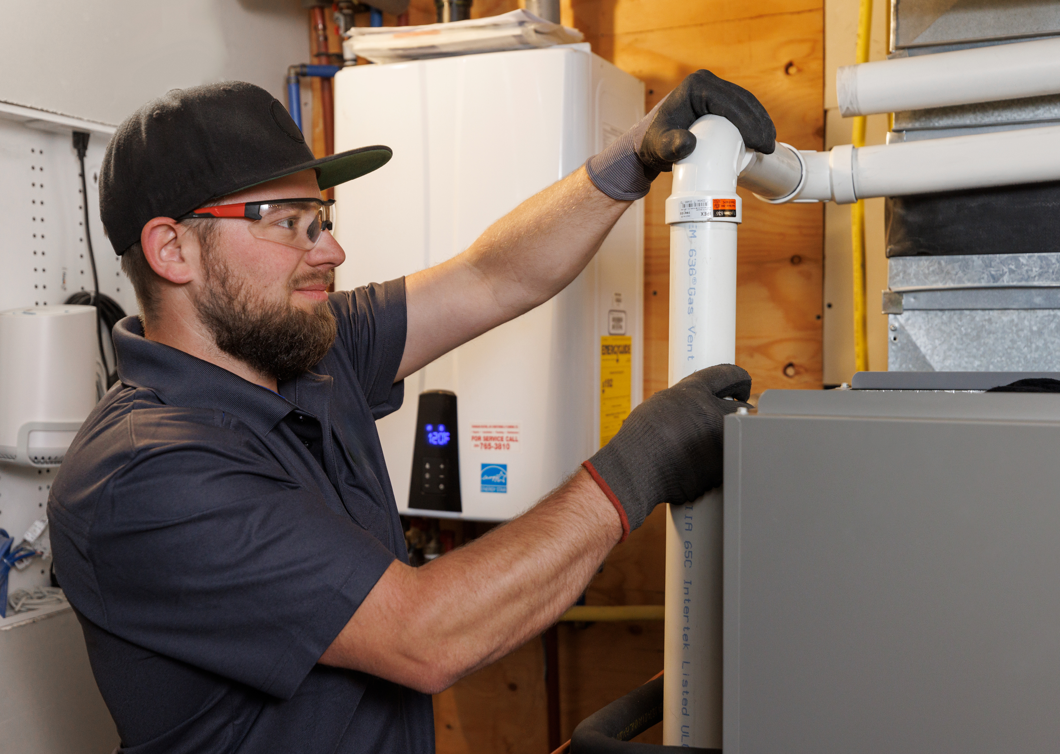 An HVAC contractor checking a gas furnace pipe.