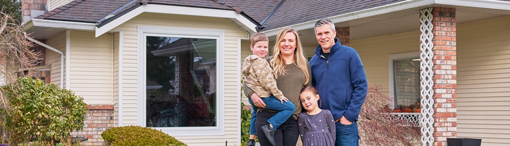 A family of four standing outside their home