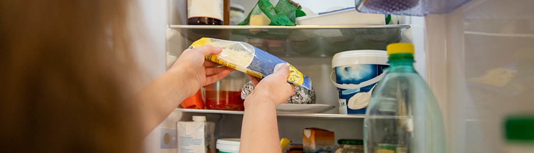 Women pulling cheese out of a refrigerator to check it for spoilage.