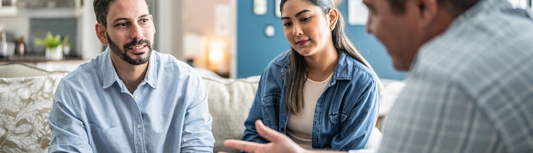 A couple talking to a contractor in their home about heat pumps.