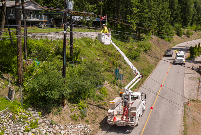 A utility workers in a bucket truck wearing safety gear are patrolling a power pole to make sure it’s safe to restore electricity