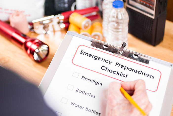A person using a checklist to organize their emergency preparedness kit.