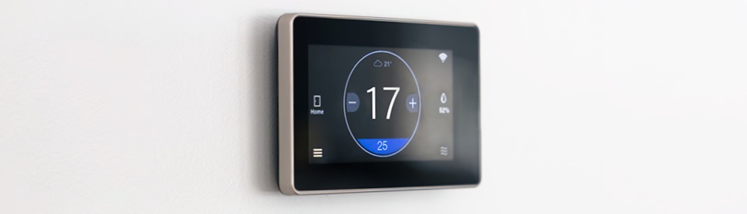 Smart digital thermostat mounted on a white wall, displaying a temperature setting of 17°C with weather and connectivity icons.