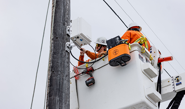 PLT crew members in a bucket, working on a weather station monitor.