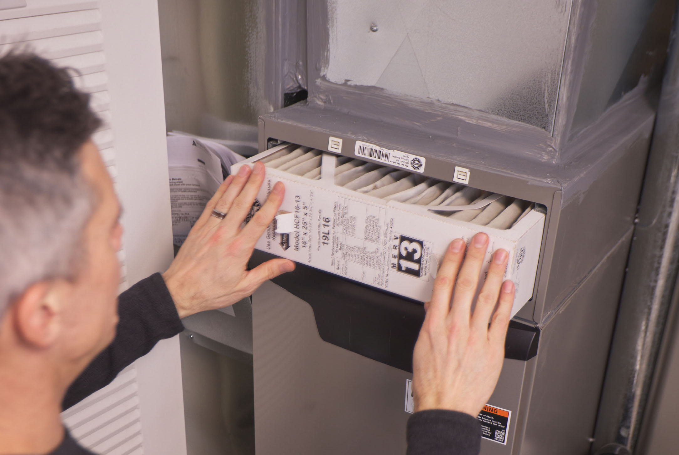 26-035-5-emergprep-4-inline-1 Person checking a heat pump air filter to help the system run efficiently during a heat wave.