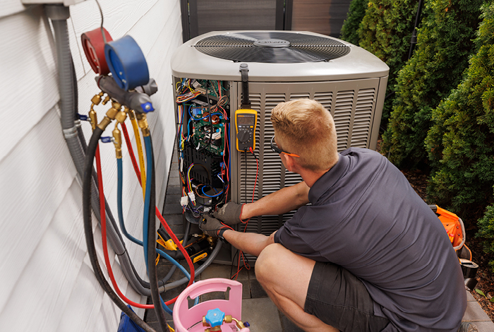 26-144-5-dualfuel-relaunch-blog-inline-700x470-4 An HVAC contractor servicing a heat pump.
