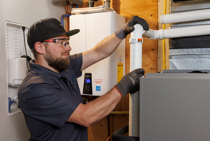 26-144-5-dualfuel-relaunch-blog-inline-700x470-5 An HVAC contractor checking a gas furnace pipe.