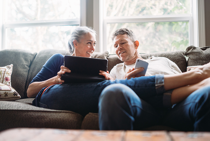 26-144-5-dualfuel-relaunch-blog-inline-700x470-6 Two people on a couch looking at a phone and tablet.