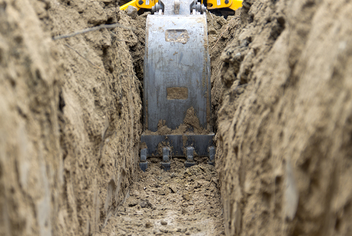 Heavy duty machine digging inside trench.