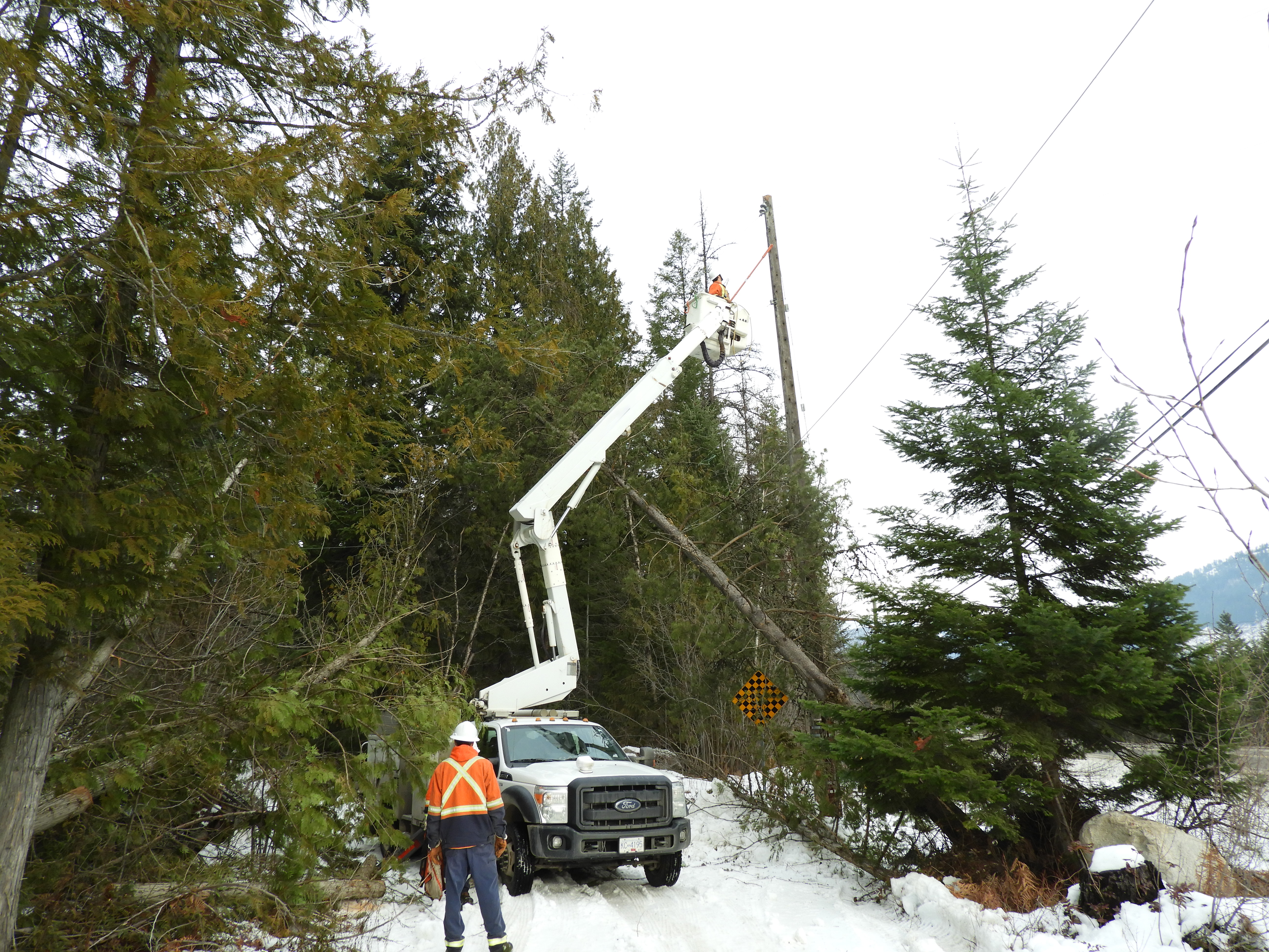 A utility truck moving a worker up to a powerline