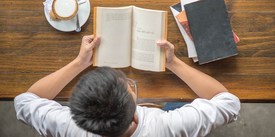 5-fresh-activities-to-do-while-you-are-staying-at-home-during-COVID-19-books Person sitting at a table reading a book