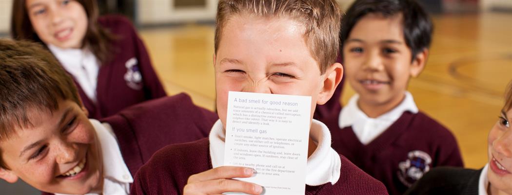 A elementary school boy smelling a natural gas scratch 'n sniff card. (18-150.13)