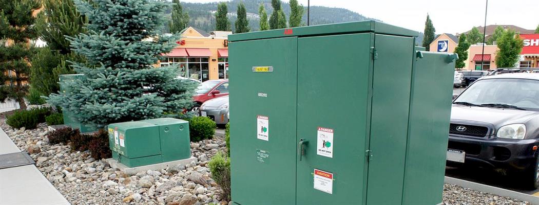 A padmounted transformer on a grassy median in a parking lot. (18-150.13)