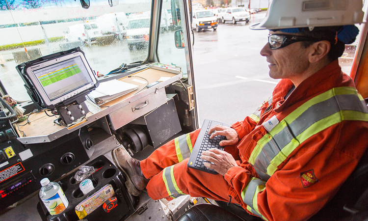 A FortisBC natural gas field crew employee, sitting inside the utility vehicle, accessing the project data via the on-board computer.